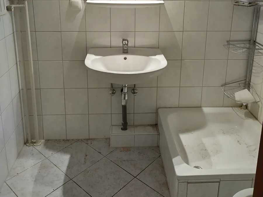 Leer geräumtes Bad mit Waschbecken und Duschwanne nach einer Räumung