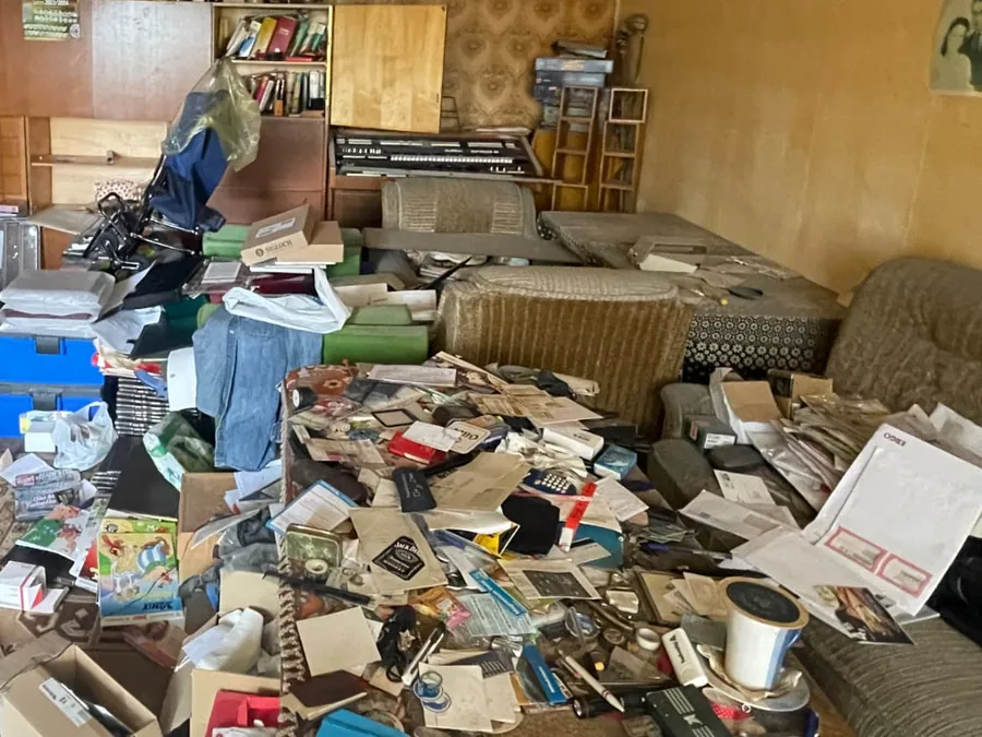 Unterlagen, Bücher und Hausrat auf dem Boden eines Wohnzimmers vor der Räumung